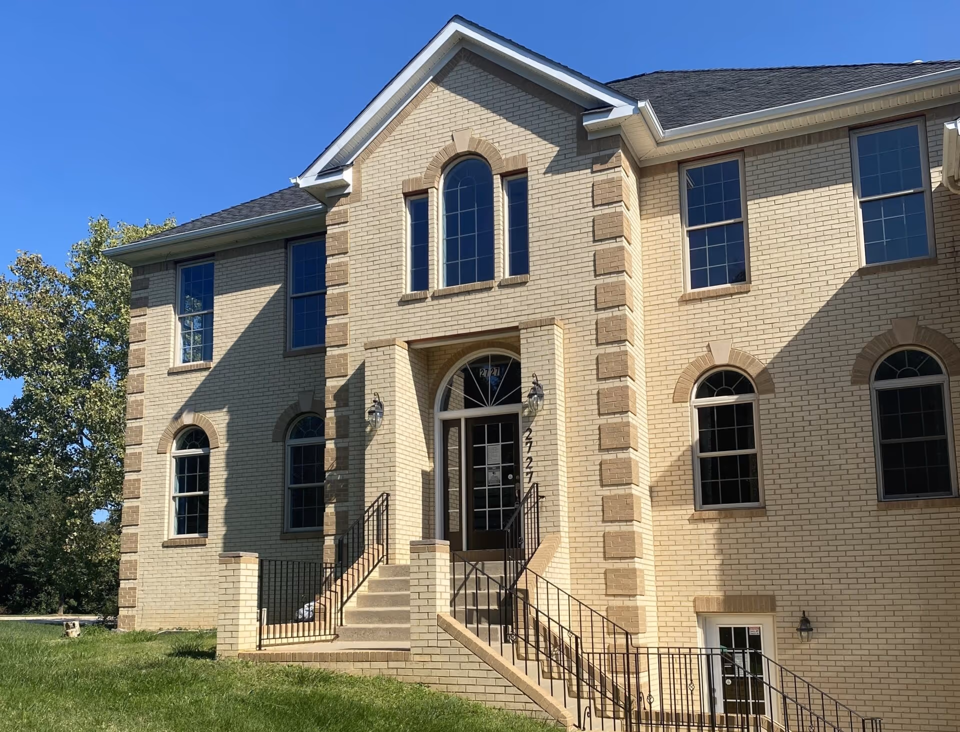 A tan brick senior living facility with arched windows and a central front entrance.