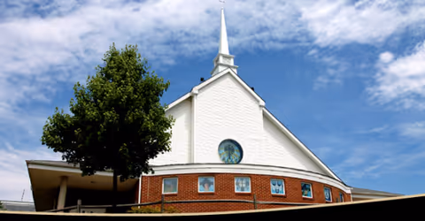 Exterior view of Carroll Lutheran Village building with brick base, white upper facade, and steeple
