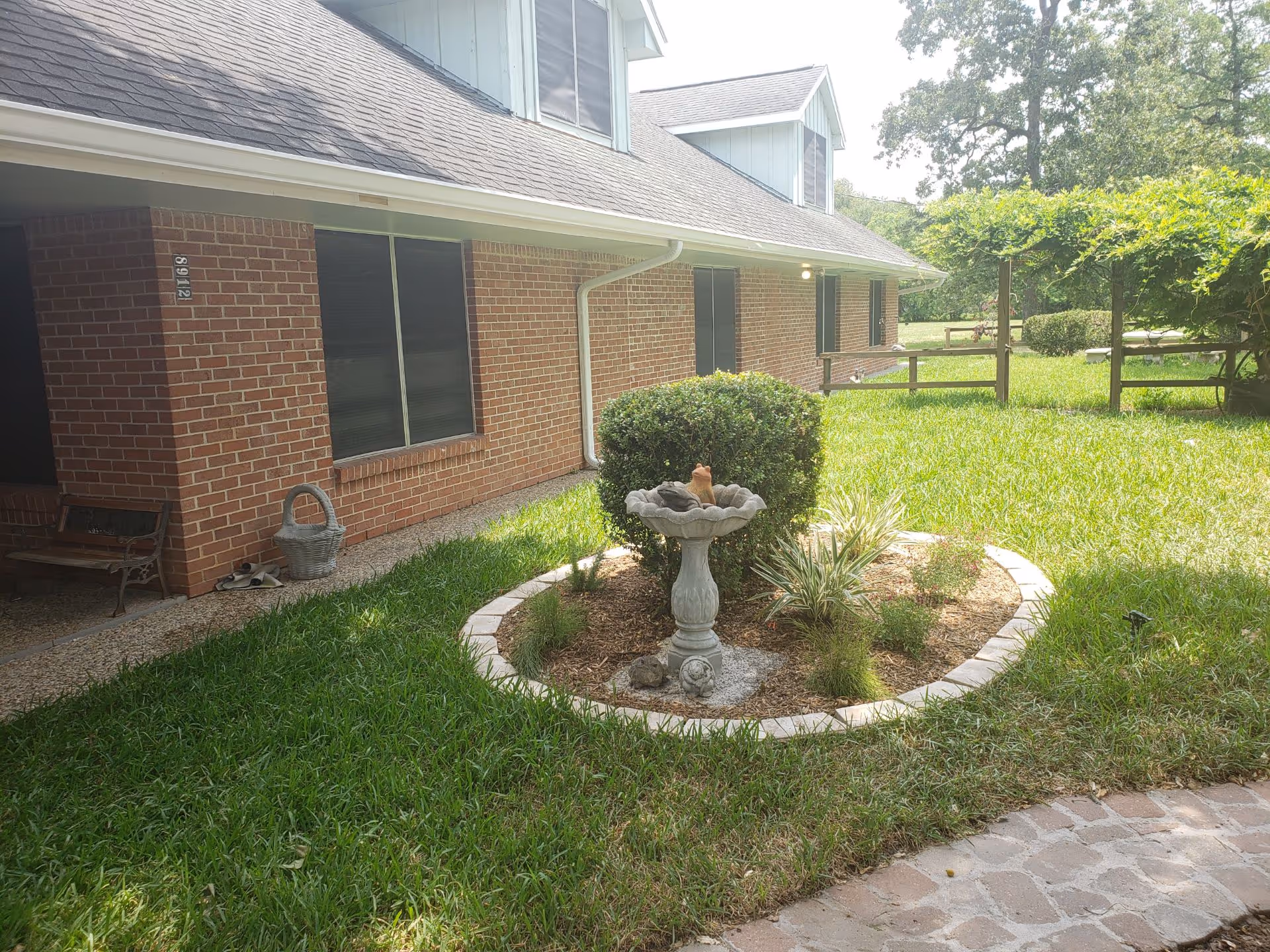 Brick senior living building with circular stone birdbath surrounded by plants and grass