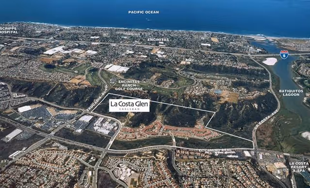 Aerial view of the La Costa Glen facility and surrounding areas in Carlsbad, California, showing nearby landmarks such as Encinitas Ranch Golf Course, Pacific Ocean, Scripps Hospital, Batiquitos Lagoon, and La Costa Resort & Spa. The image highlights roads and neighborhoods around the facility.