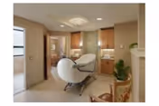 Interior of a senior facility with a white recliner chair, wooden cabinets, and potted plants.