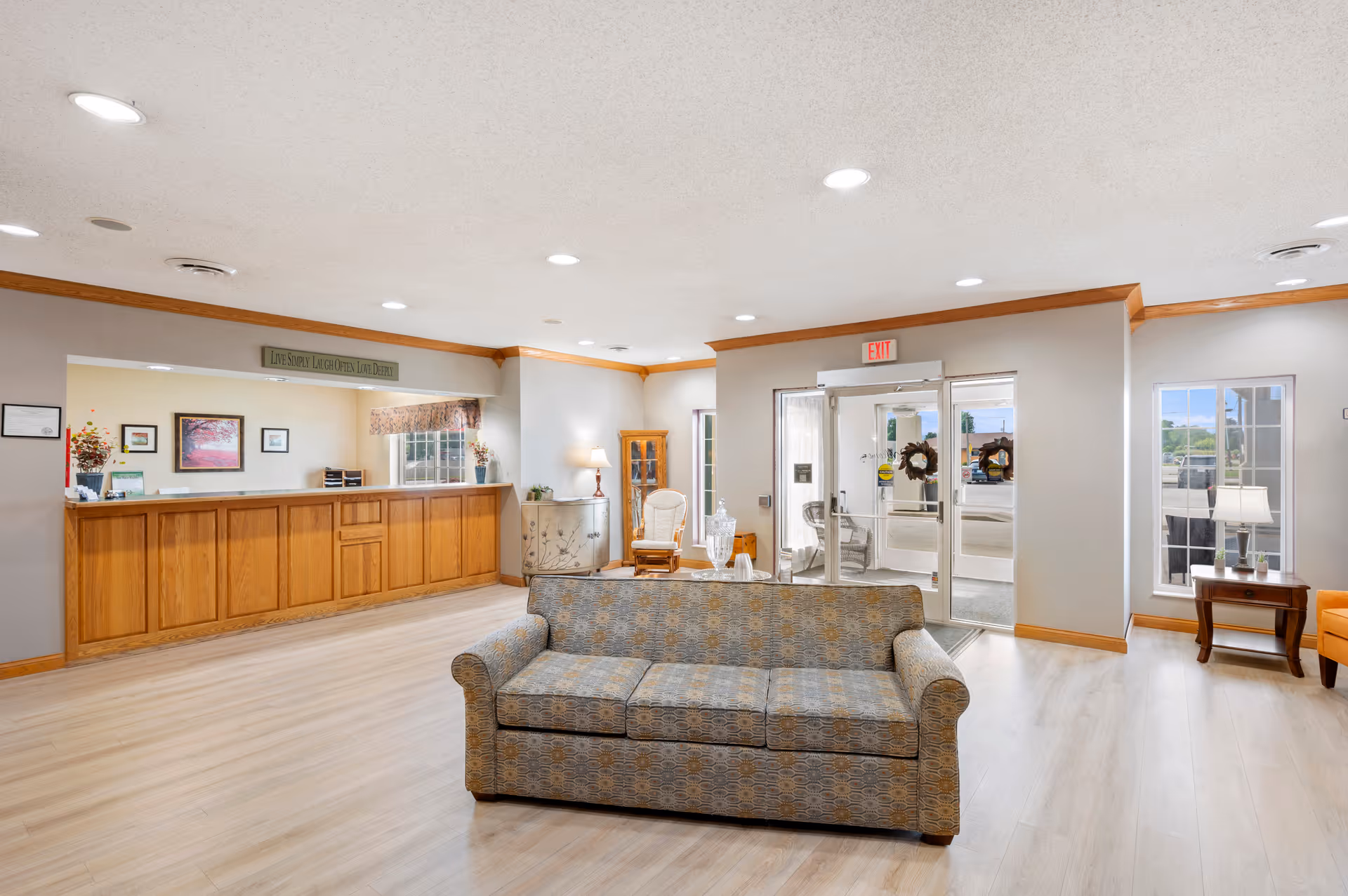 Spacious senior living facility lobby with a reception desk, couch seating and glass entrance doors.
