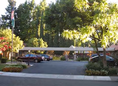 The WaterLeaf at Land Park exterior entrance with trees, flagpoles, and a driveway.