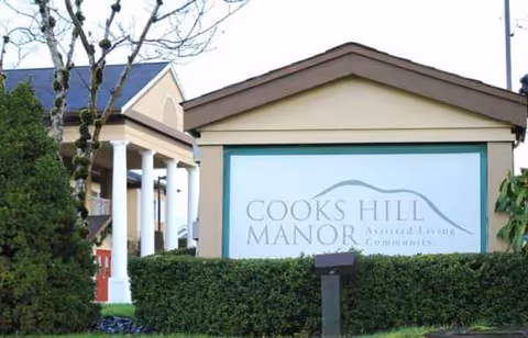 Front exterior of an assisted living facility with a Cook's Hill Manor sign.