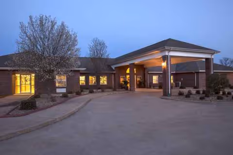 Exterior view of Oak Manor Nursing Center entrance at dusk with a covered porte-cochere.