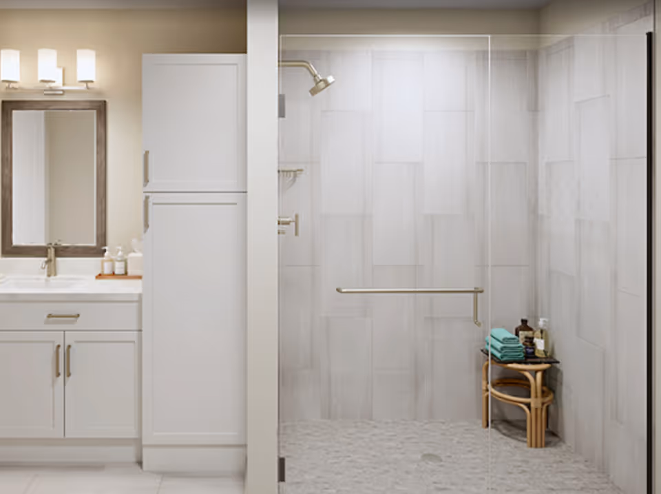 A modern bathroom featuring a white vanity with a sink, a large mirror with three light fixtures above it, and a tall white cabinet. Next to the vanity is a walk-in shower with a glass door, tiled walls, a showerhead, a grab bar, and a small wooden stool holding folded teal towels and various toiletries.