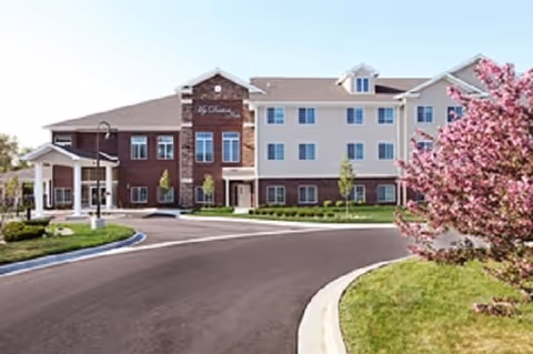 Exterior view of My Doctor's Inn assisted living building with curved driveway and flowering tree.