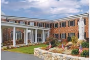 Brick senior living facility exterior with a landscaped rock garden and flags.