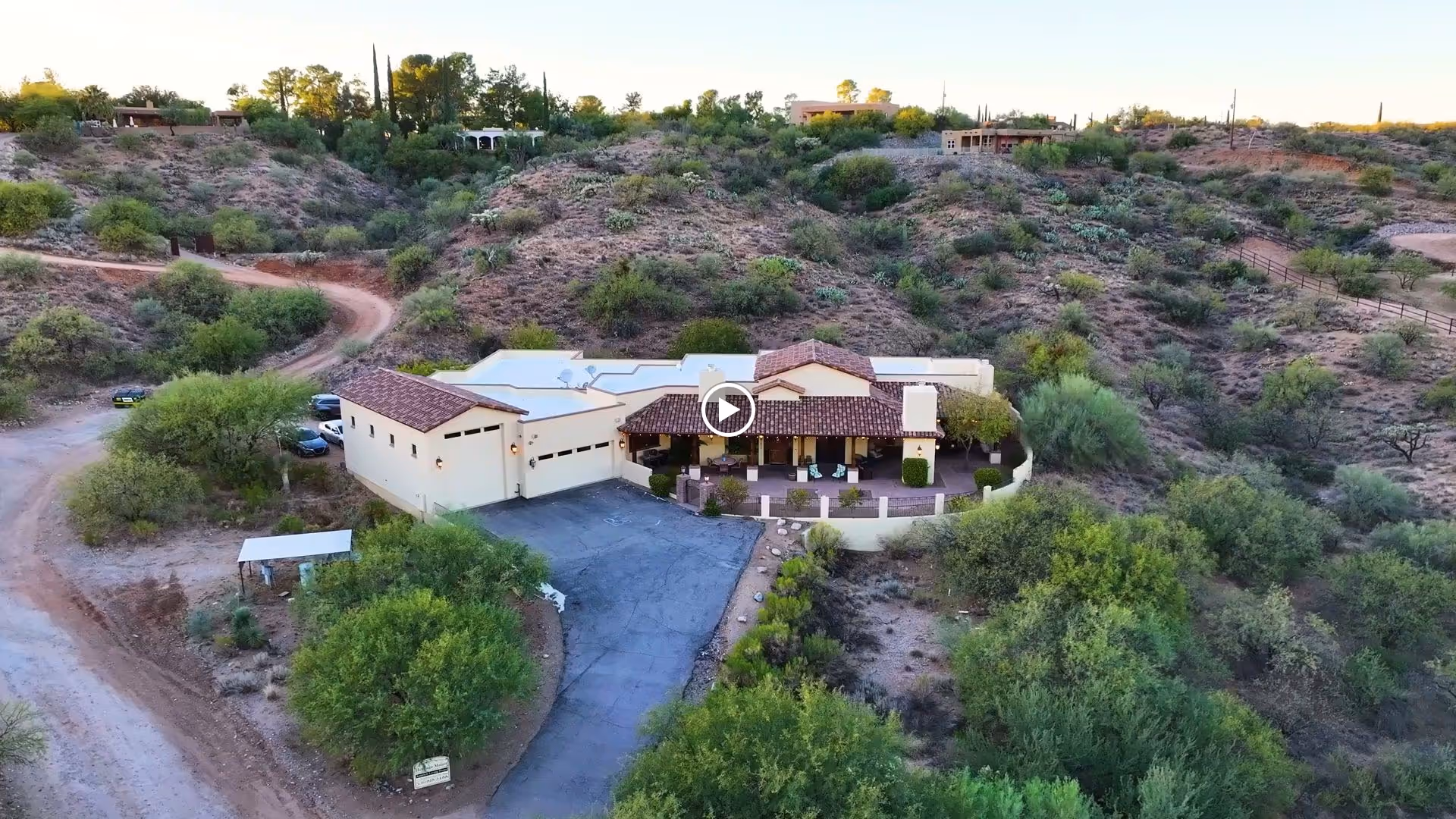 Aerial view of a single-story assisted living building with a tiled roof, driveway, and surrounding desert hills.