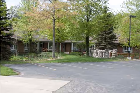Exterior view of Yorkshire Manor with a parking lot, trees, and building entrances.