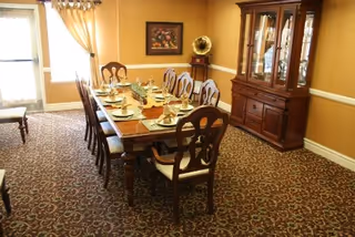 Formal dining room with a long wooden table set for a meal, matching chairs, a china cabinet and decorative gramophone.