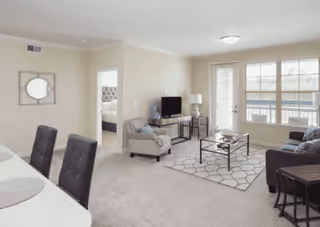 Bright living room with a sofa, armchair, coffee table, TV and a door/window leading to a balcony.