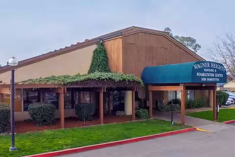Exterior view of Wagner Heights Nursing and Rehabilitation Center with a covered entrance and green landscaping.