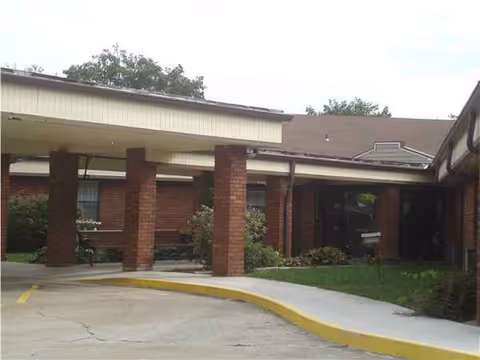 Brick senior living facility front with a covered entrance and landscaping.