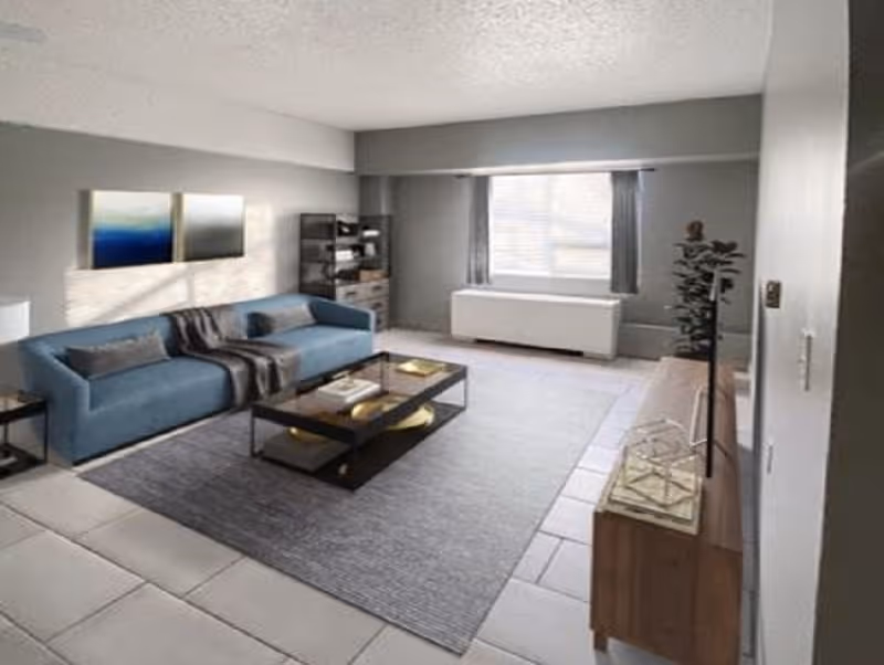 A modern living room with a blue sofa adorned with pillows and a throw blanket, a glass coffee table with decorative items, a large window with curtains, a wooden TV stand with a flat-screen TV, a potted plant, and two abstract paintings on the wall. The floor is tiled with a large area rug in the center.
