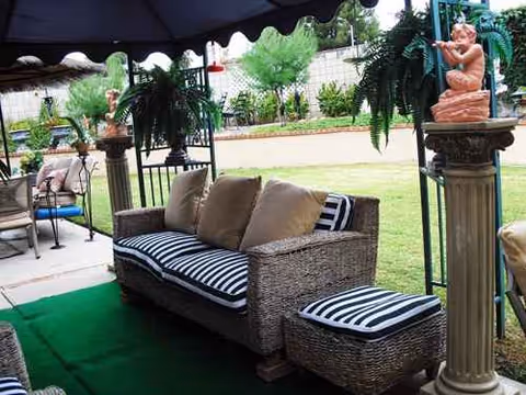 Outdoor patio at Golden Years with wicker seating, striped cushions, and potted plants.