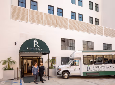 Entrance of Regency Palms Long Beach with a bus parked beside the front doorway.