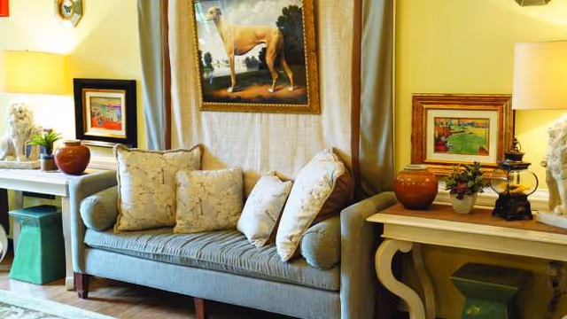 Cozy living room at Greenfield of Fredericksburg with a tufted sofa, lamps, and framed art.