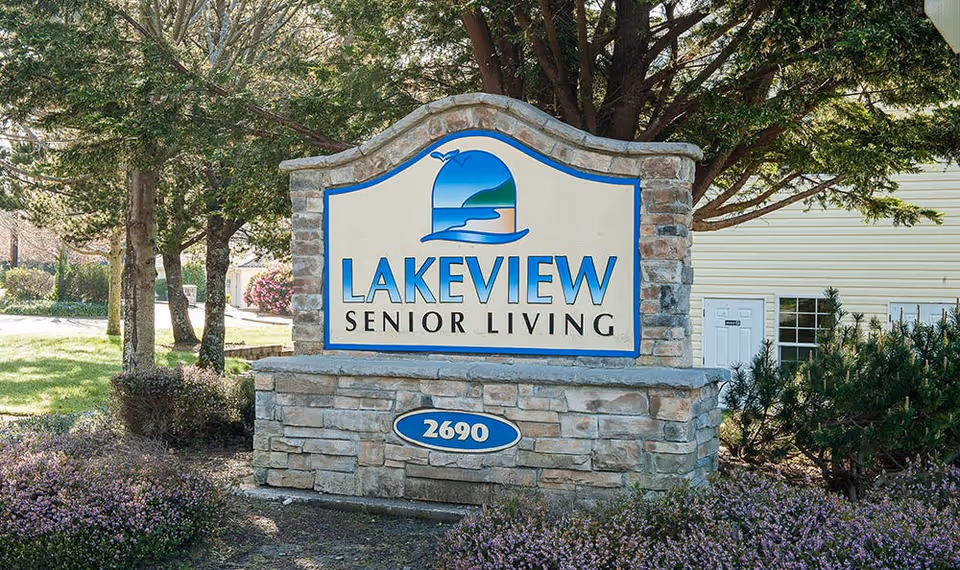 Stone entrance sign that reads "LAKEVIEW SENIOR LIVING" with landscaping, trees, and a building in the background.