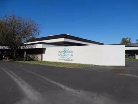 White modern facility facade with Gardenview Manor sign and parking area.