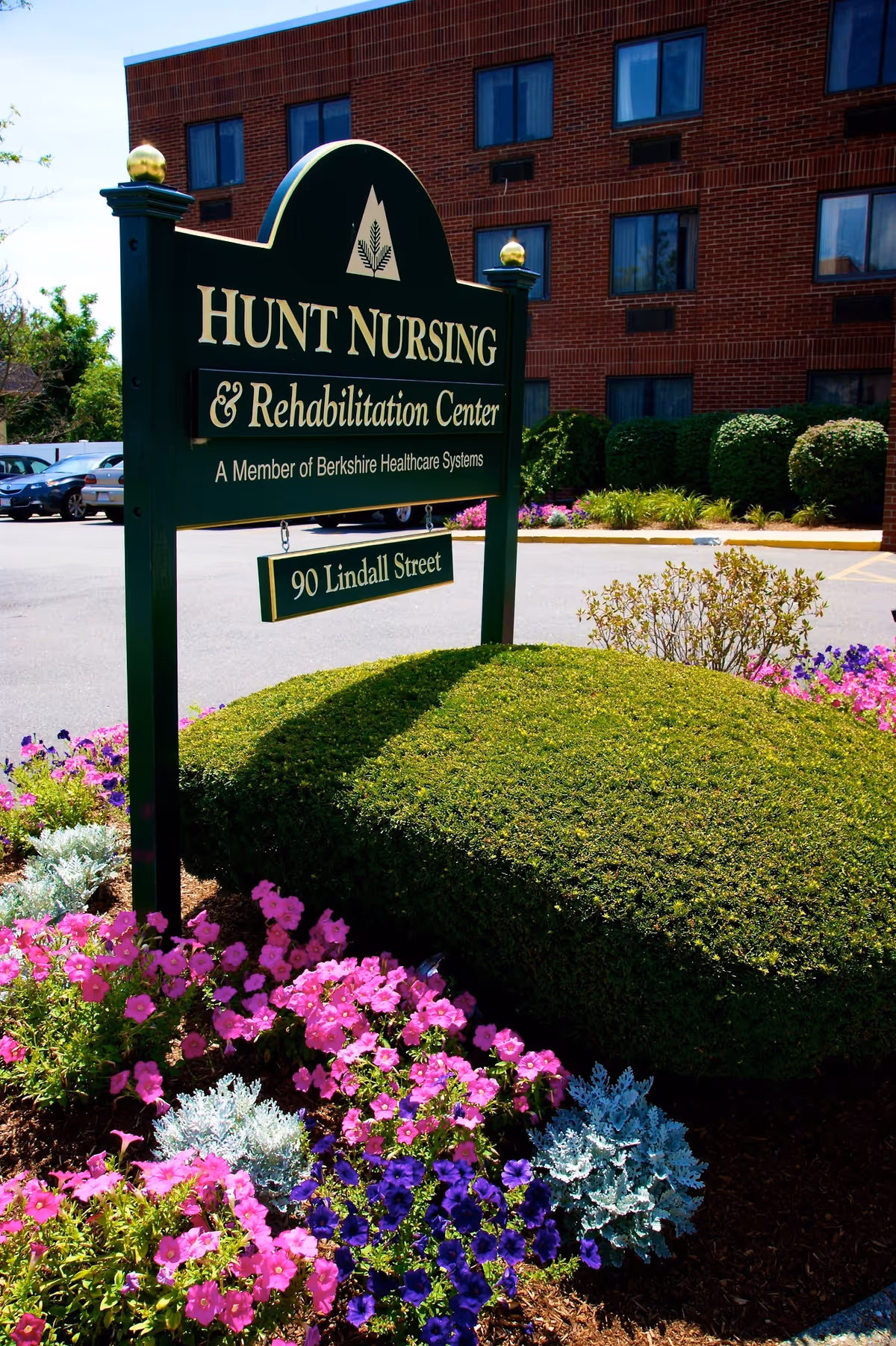 Sign for Hunt Nursing & Rehabilitation Center surrounded by colorful flowers.