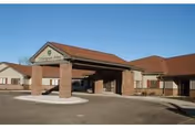 Front entrance of Bartels Lutheran Retirement building with a covered porte-cochere and red roof under a clear blue sky.