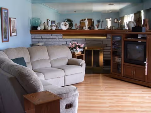 Cozy living room with beige sofa, brick fireplace, and wooden entertainment cabinet.