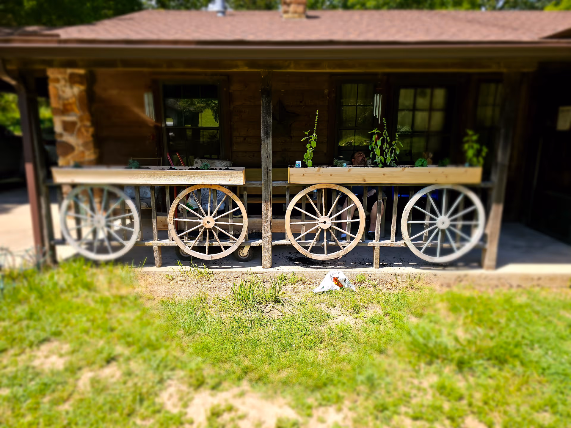 A rustic porch with wagon-wheel railings and planter boxes in front of a wooden building.