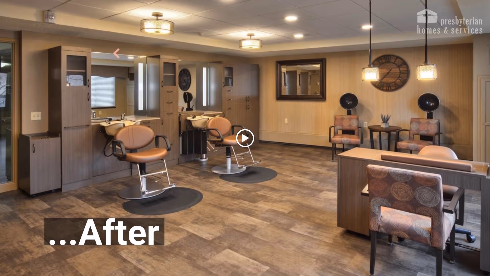 Interior view of a salon area with two styling chairs in front of mirrors and sinks, a desk with a chair, and a seating area with two chairs and hair dryers. The room has wood flooring, beige walls, and ceiling lights.
