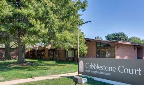 Brick exterior of Cobblestone Court with a large sign and green lawn.
