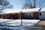 Front view of a single-story brick senior living building with snow-covered lawn and lamp post.