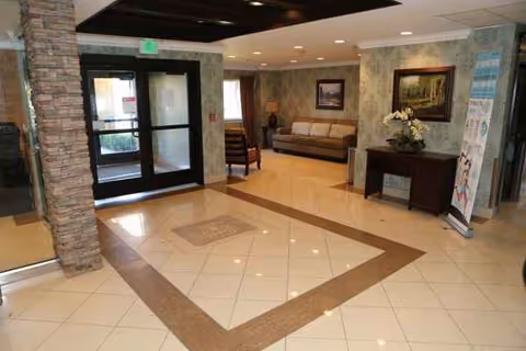 Senior living facility lobby with tiled floor, stone column, glass doors, and seating area.
