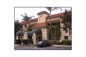 Exterior view of a two-story residential building with a tiled roof, palm trees, and a parked car in front of the entrance at Casa Escondida facility.