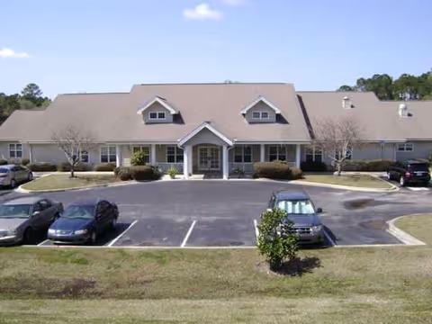 Exterior view of a single-story senior living facility with a parking lot.