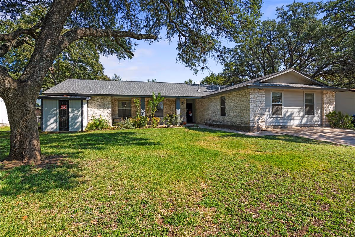 Single-story stone-and-siding senior living facility with a green lawn and large tree.
