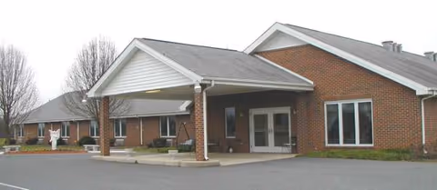 Brick senior living facility with a covered entrance and adjacent parking lot.