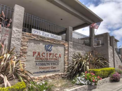 Exterior view of Pacifica Senior Living Mission Villa entrance with stone sign and landscaping.