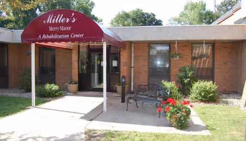 Front entrance of Miller's Merry Manor rehabilitation center with a maroon canopy and benches.