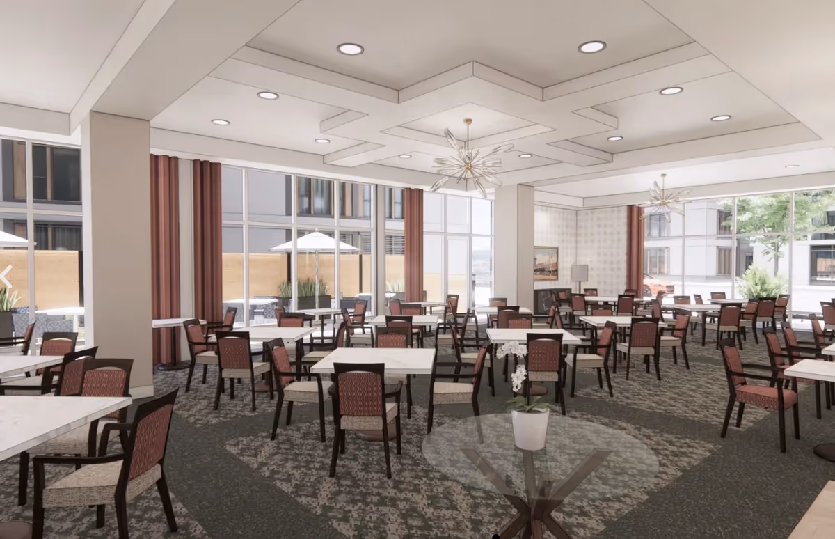 Spacious dining room with multiple tables and chairs, large windows, and modern ceiling light fixtures.