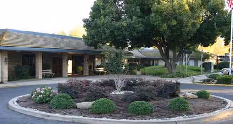 Exterior view of Park Merced Assisted Living with circular landscaped island and walkway.