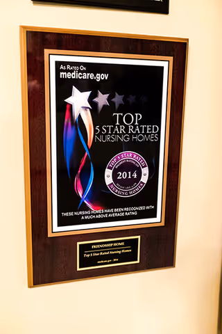 A framed plaque on a wall displaying a 2014 Top 5 Star Rated Nursing Homes award from medicare.gov, recognizing nursing homes with a much above average rating.