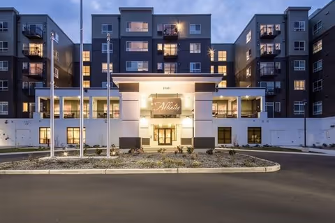 Exterior front view of a multi-story senior living facility named Affinity at Covington during dusk, with lights on inside the building and a driveway in front.