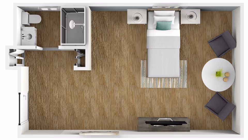Top-down floor plan of a small studio apartment with a single bed, two nightstands with lamps, two chairs and a round table with a plant, a TV on a stand, and a bathroom with a toilet, sink, and shower.