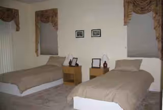 Two twin beds with nightstands and lamps in a simple bedroom.
