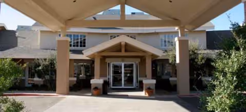 Entrance of Brookdale Remington Park with a covered drop-off and beige pillars.