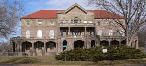 Exterior view of a brick geriatric center building with arches and a red roof.