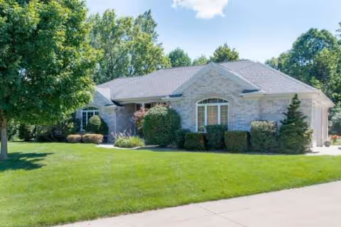 Exterior view of Western Hills Living: single-story stone building with manicured lawn and trees.