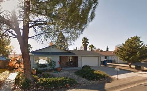 Exterior view of a single-story Woodcliff Care Home with a front yard and driveway.