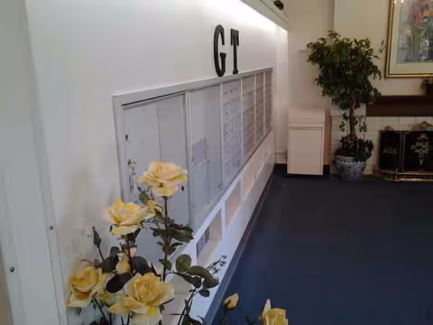 Wall-mounted mailboxes along a hallway with yellow roses in the foreground.