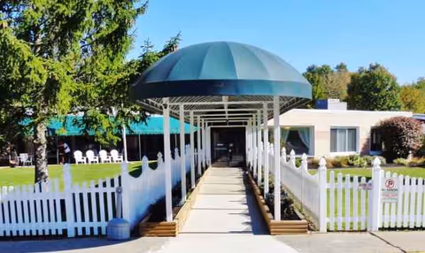 Exterior view of Betsy Ross Nursing Facility with a covered walkway and white picket fence.